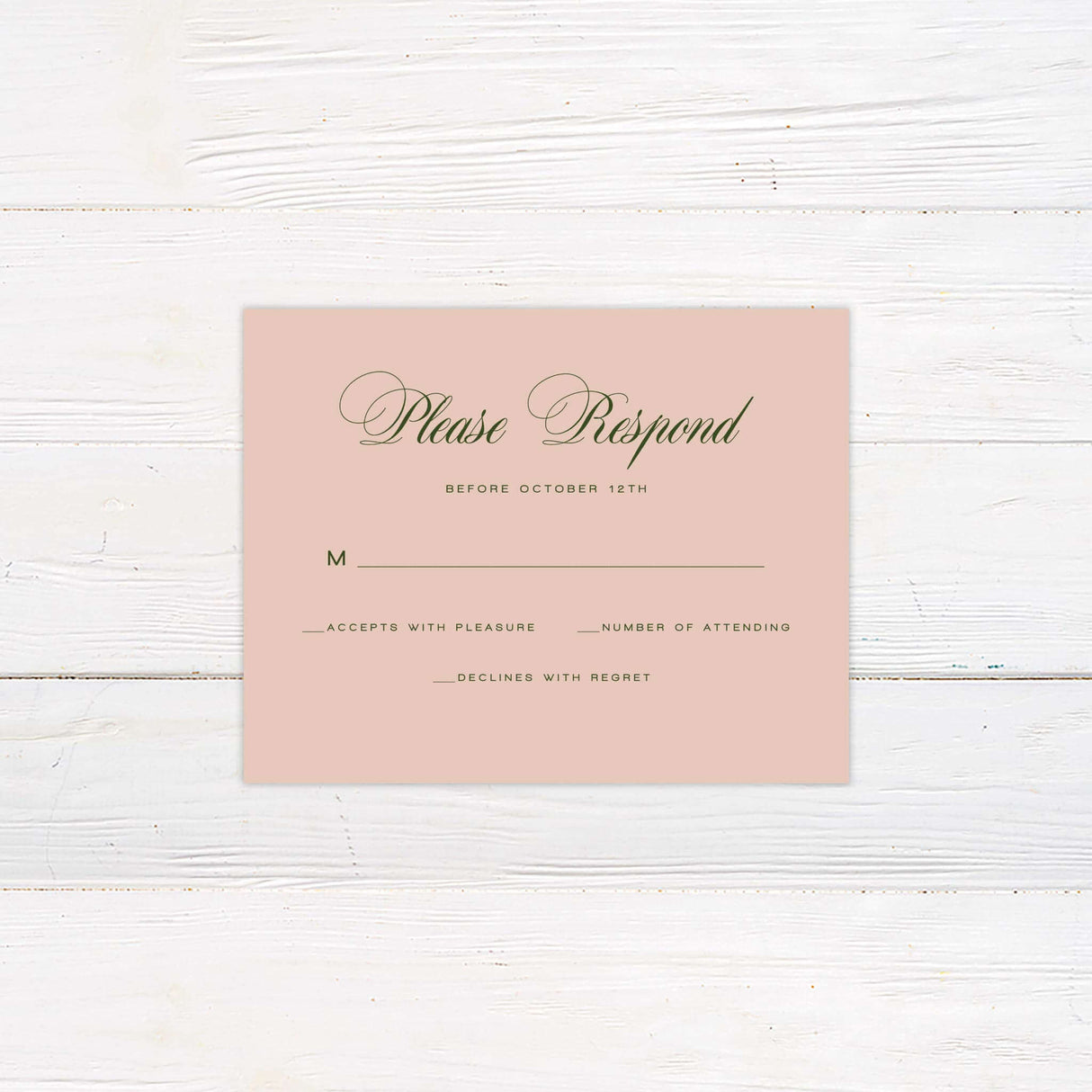 Blush pink wedding RSVP card with elegant green script font, minimal floral accent, and classic layout.