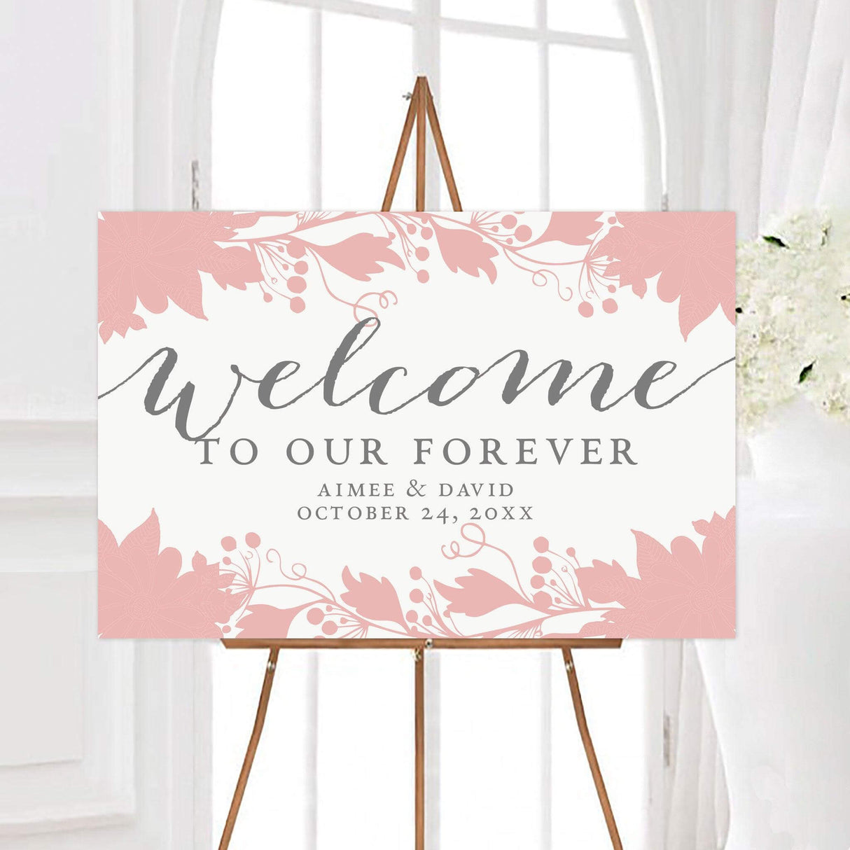 Elegant floral wreath wedding welcome sign featuring soft floral illustrations framing a clean background with romantic script lettering. The personalized design displays the couple’s names and wedding date beneath the phrase “Welcome to Our Forever.”