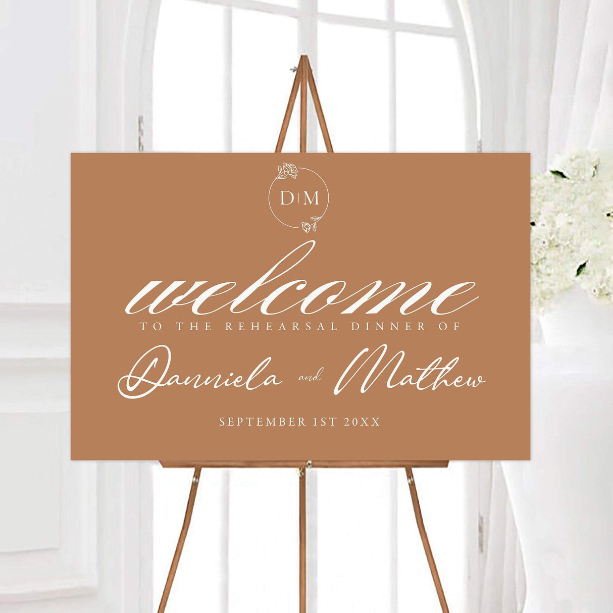 Terracotta floral monogram rehearsal dinner welcome sign featuring white calligraphy, a delicate floral monogram, and personalized couple names. The warm brown design includes the rehearsal dinner date beneath the names.