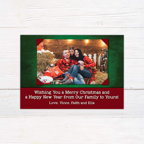 Rustic Christmas card with framed family photo, red and green design, and customizable holiday greeting with personalized family name.