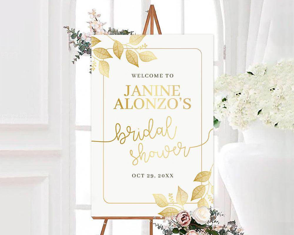 A gold leaves bridal shower sign with a white background and elegant botanical frame. The design features soft gold foliage and modern script text.
