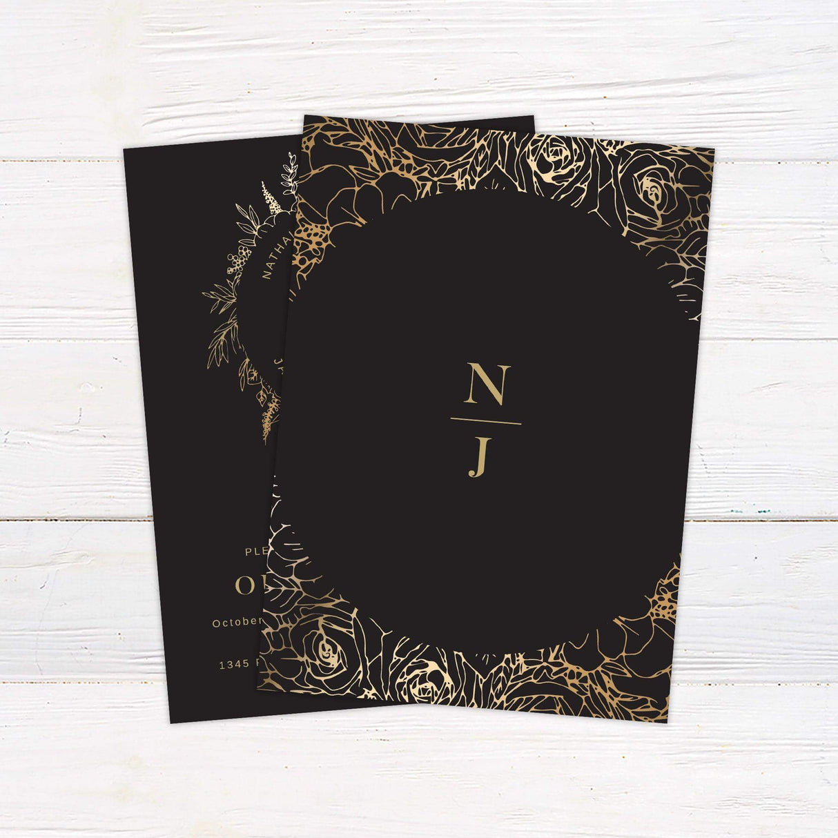 Black wedding invitation with gold monogram and botanical wreath, featuring modern typography and elegant gold accents