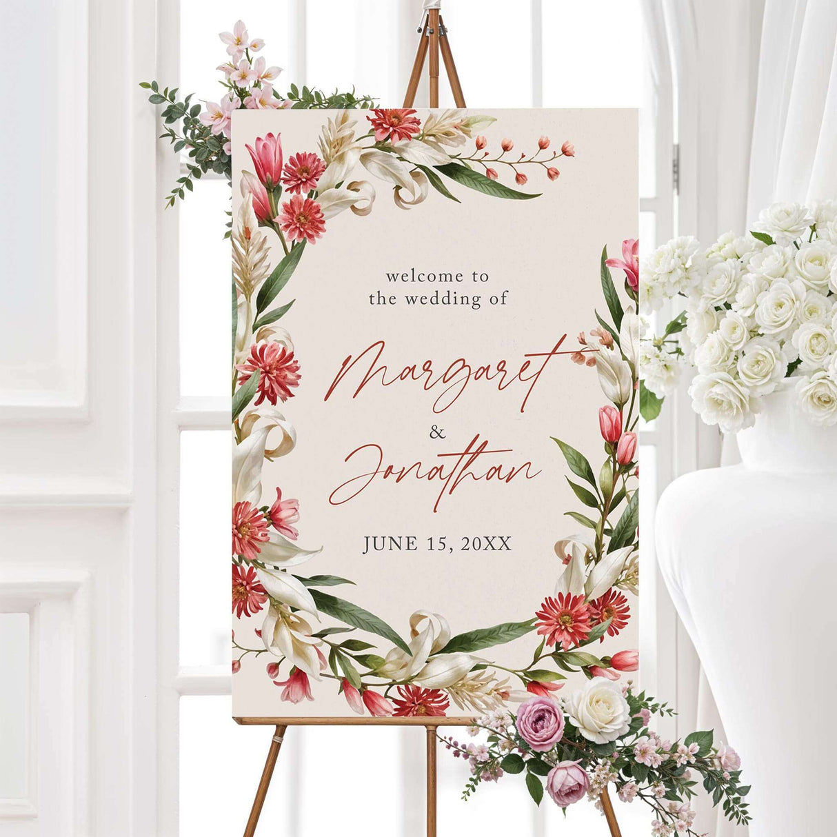 Elegant welcome sign with a floral design featuring red, pink, and white flowers with green leaves arranged in a wreath. The text is in a mix of script and serif fonts.