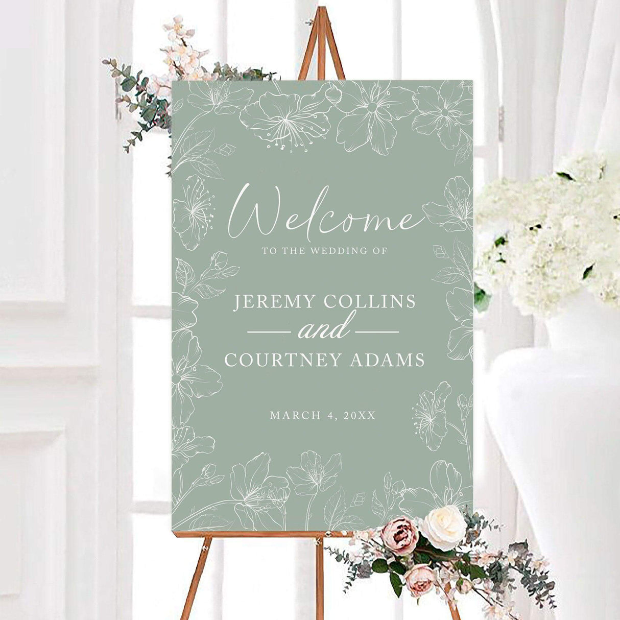 Green sakura wedding welcome sign featuring delicate white hand-drawn flowers, leaves, and botanical branches around the border. Elegant script and serif lettering displays the couple’s names and wedding date.