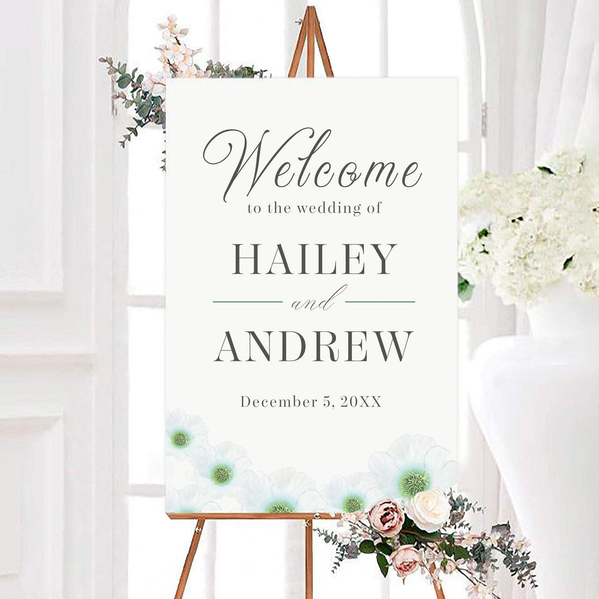 Elegant green whisper wedding welcome sign featuring soft white watercolor flowers along the bottom with gray typography and subtle green accents. The sign is personalized with the couple’s names and wedding date.