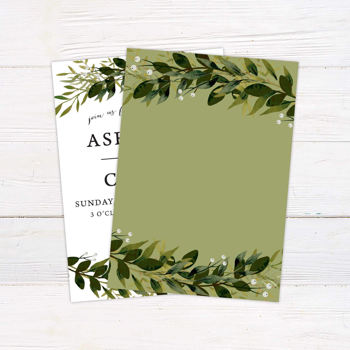 Greenery wedding invitation with top and bottom foliage border, elegant serif and script fonts on white background - back