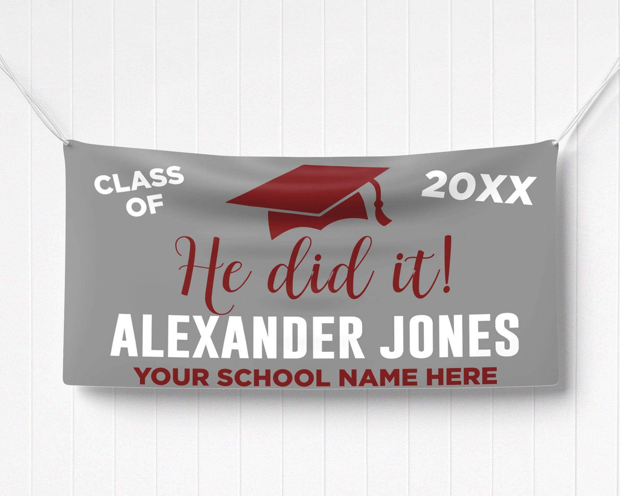 Bold "He Did It!" Graduation Vinyl Banner featuring a mortarboard cap, class year, and celebratory typography. Perfect for indoor and outdoor graduation decorations. Customizable colors and school name for any high school or college graduate. gray and red