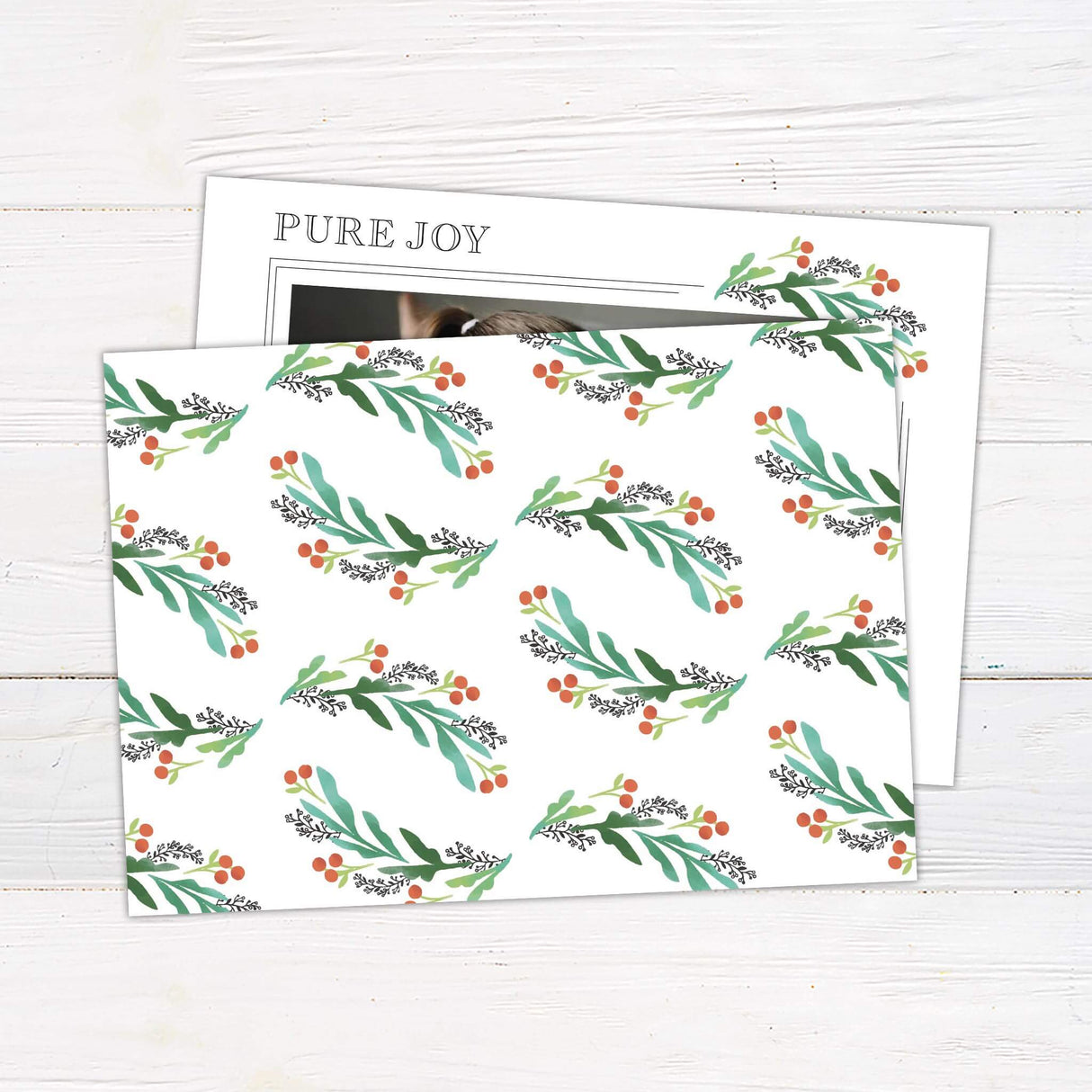 Holiday photo card featuring two children with soft watercolor holly berry corners and text reading back side