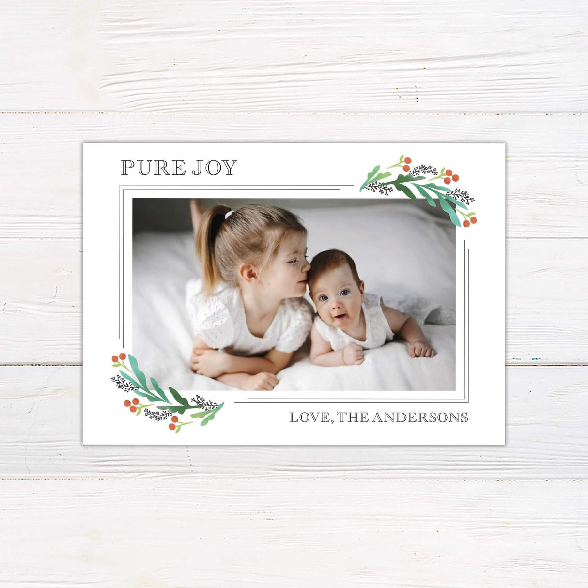 Holiday photo card featuring two children with soft watercolor holly berry corners and text reading