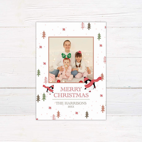 Ice Skating Christmas card with family photo frame, penguin illustrations in scarves, snowflakes, trees, and personalized Merry Christmas message.