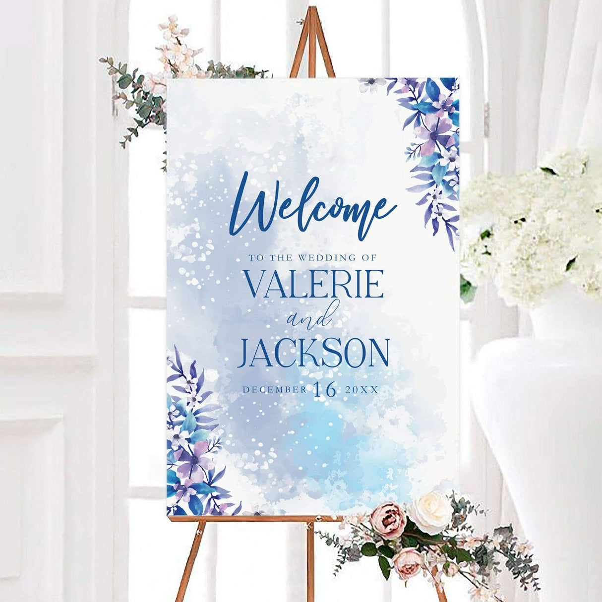 Icy floral wedding welcome sign featuring an icy blue watercolor background with blue, lavender, and white floral accents. The personalized design displays the couple’s names and wedding date in elegant typography.