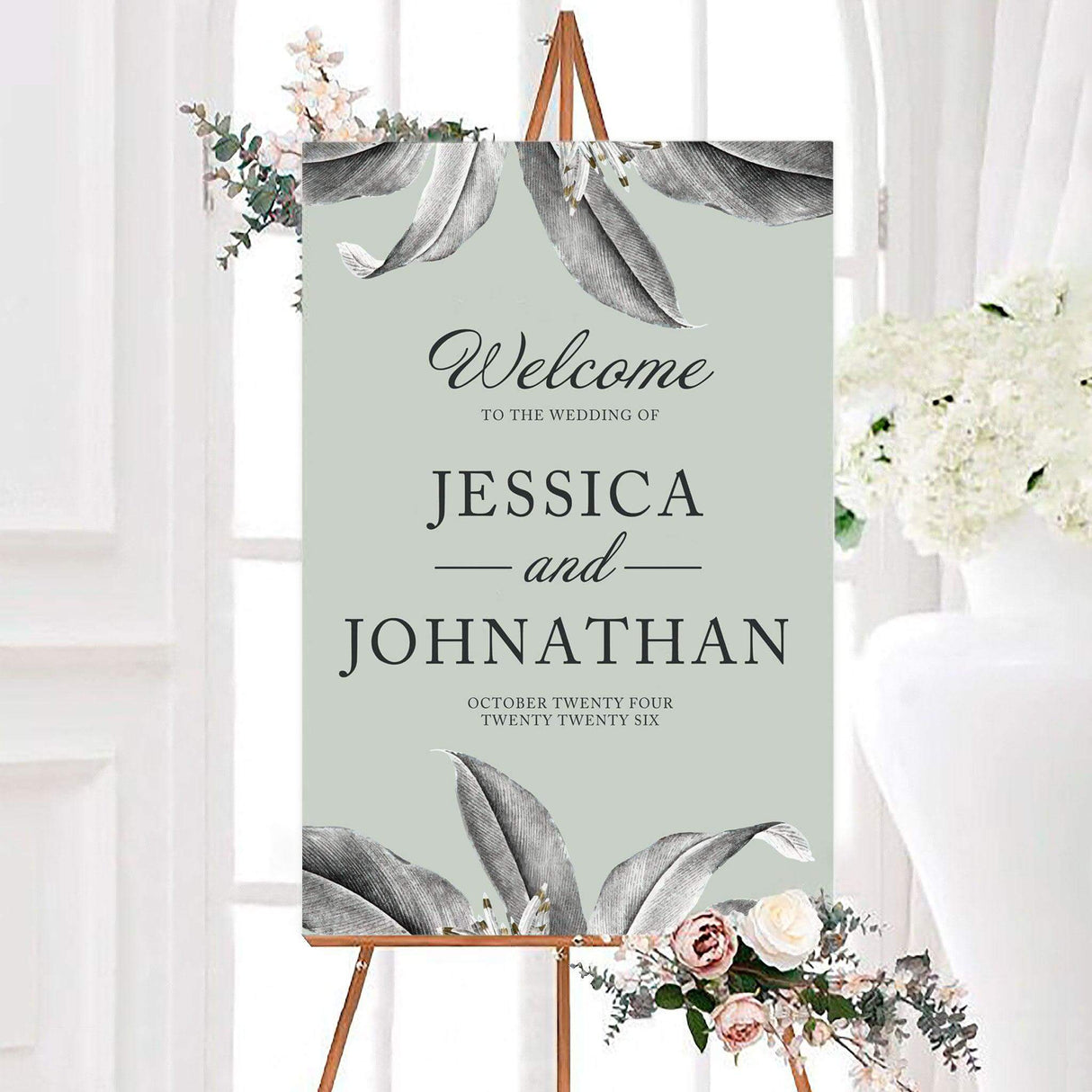 Idyllic wedding welcome sign featuring large neutral lily illustrations with elegant script and serif typography. The personalized design includes the couple’s names and wedding date on a soft muted background.
