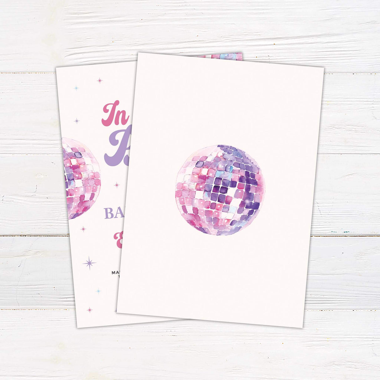 In Her Baby Era baby shower invitation featuring a pastel disco ball design on a white wooden background.