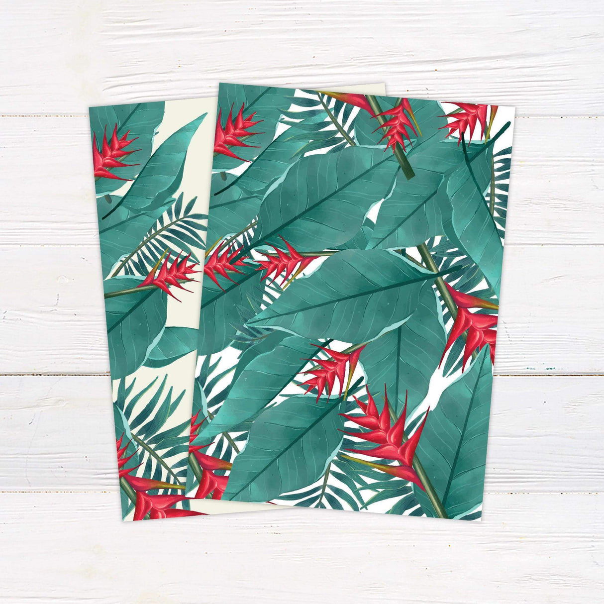 Tropical wedding invitation with green palm leaves, red tropical flowers, and elegant script text on a light pastel background - back