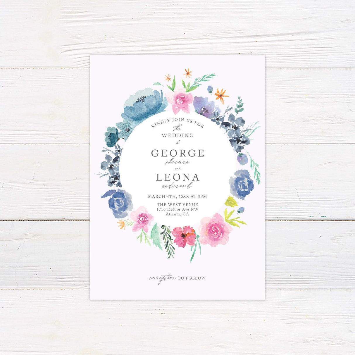 Wedding invitation with watercolor floral wreath in pink, blue, lavender, and coral, featuring elegant serif and script fonts