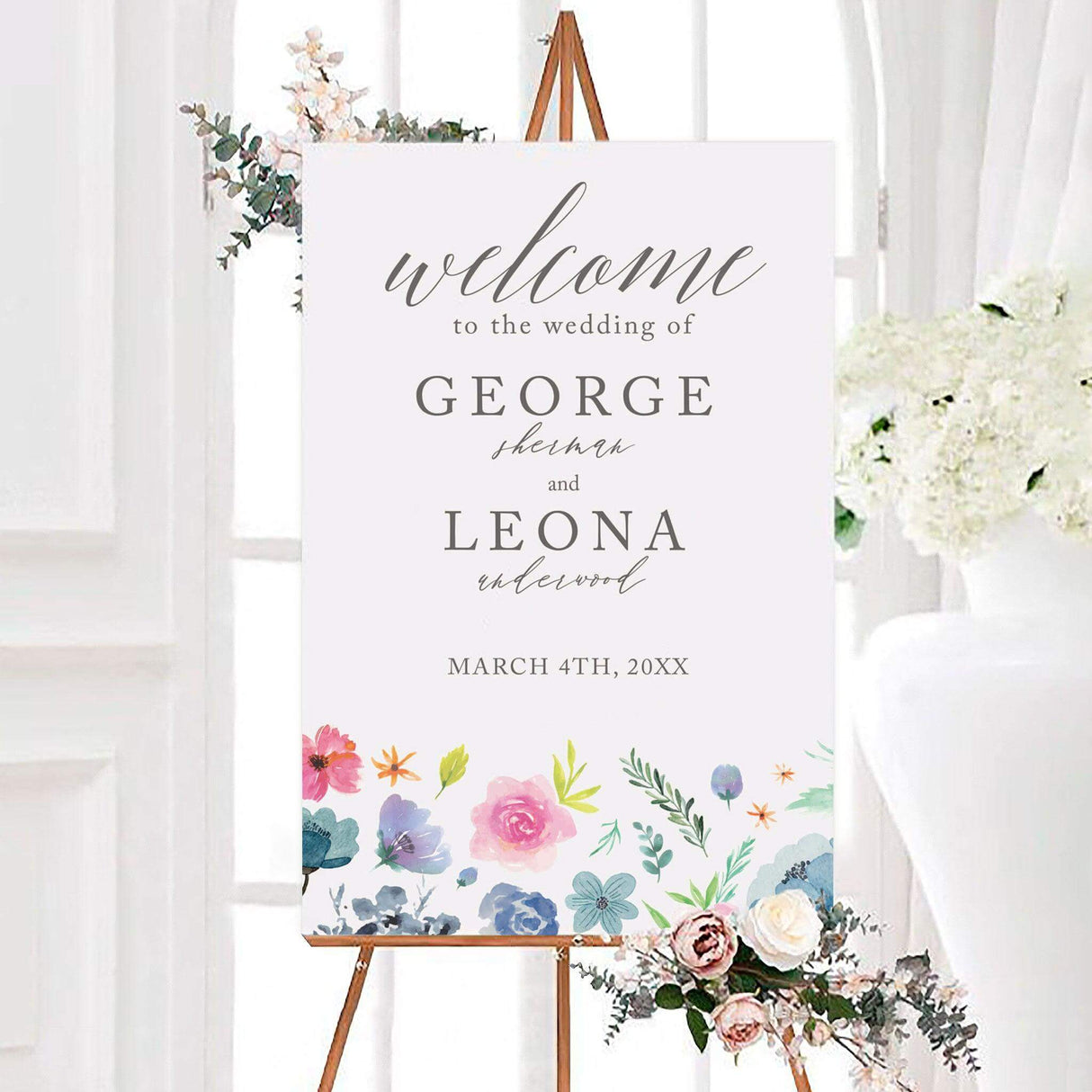 Colorful joyous bouquet wedding welcome sign with pink, blue, lavender, and green flowers along the bottom. The personalized design features elegant script, the couple’s names, and wedding date.