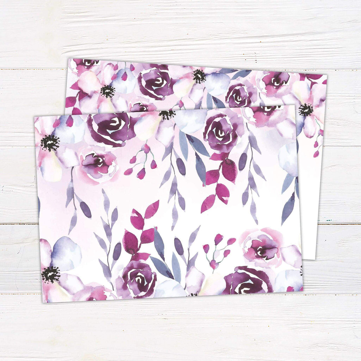 Wedding invitation with watercolor flowers in pink and purple hues, cascading from the top, with elegant script and serif text on a white background - back