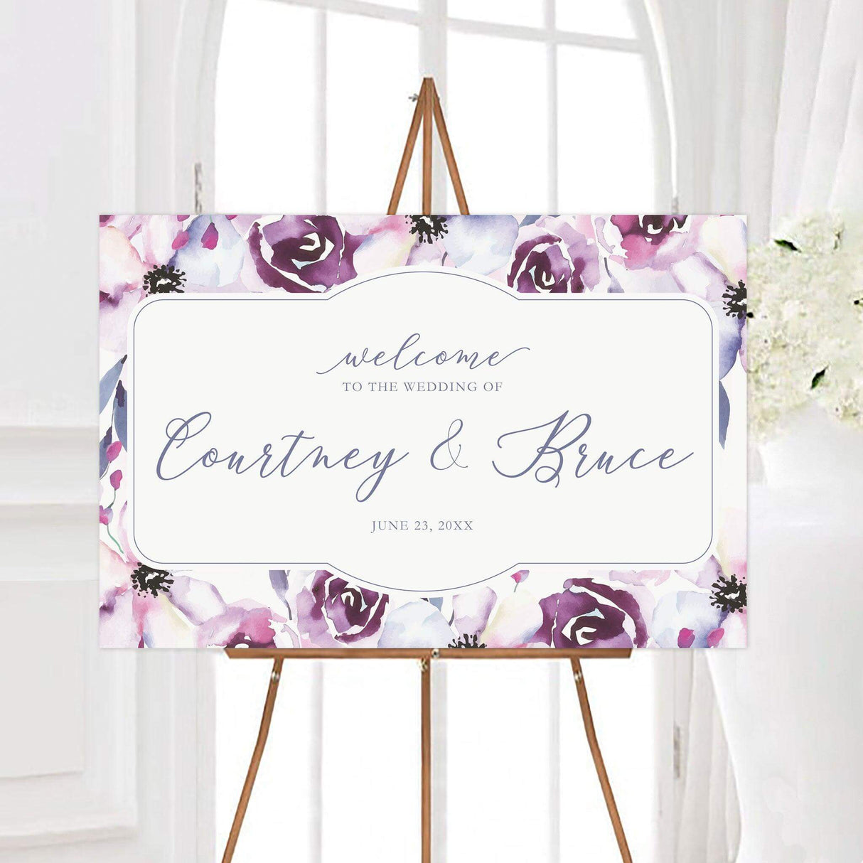 Lovely blossoms wedding welcome sign featuring purple, lavender, blush, and blue watercolor blossoms surrounding an elegant white framed center. Personalized script lettering creates a romantic floral design for a wedding ceremony or reception.