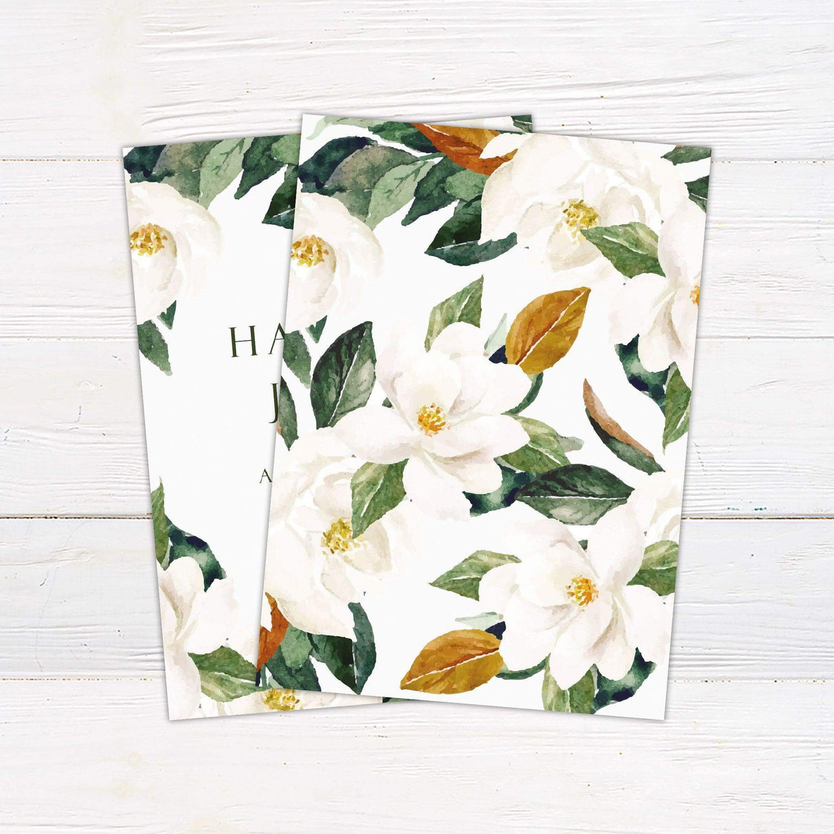 Elegant magnolia wedding invitation with white flowers and green leaves, featuring soft serif and script fonts on a pale background. - back