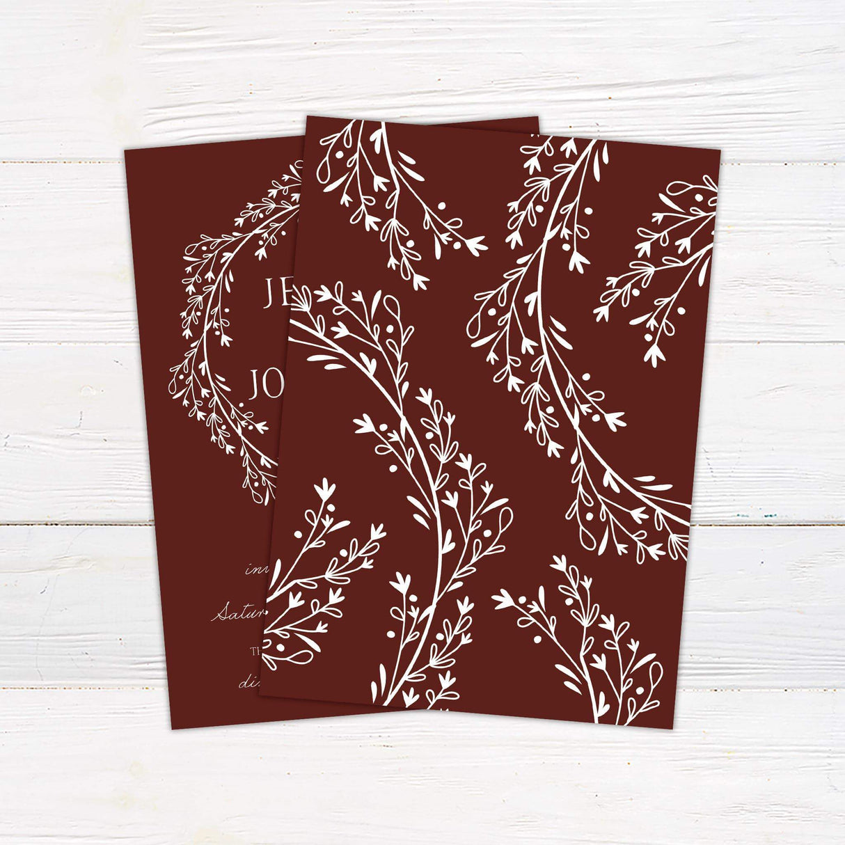 Wedding invitation with marsala red background, white floral wreath illustration, and elegant serif and script fonts for event details = back