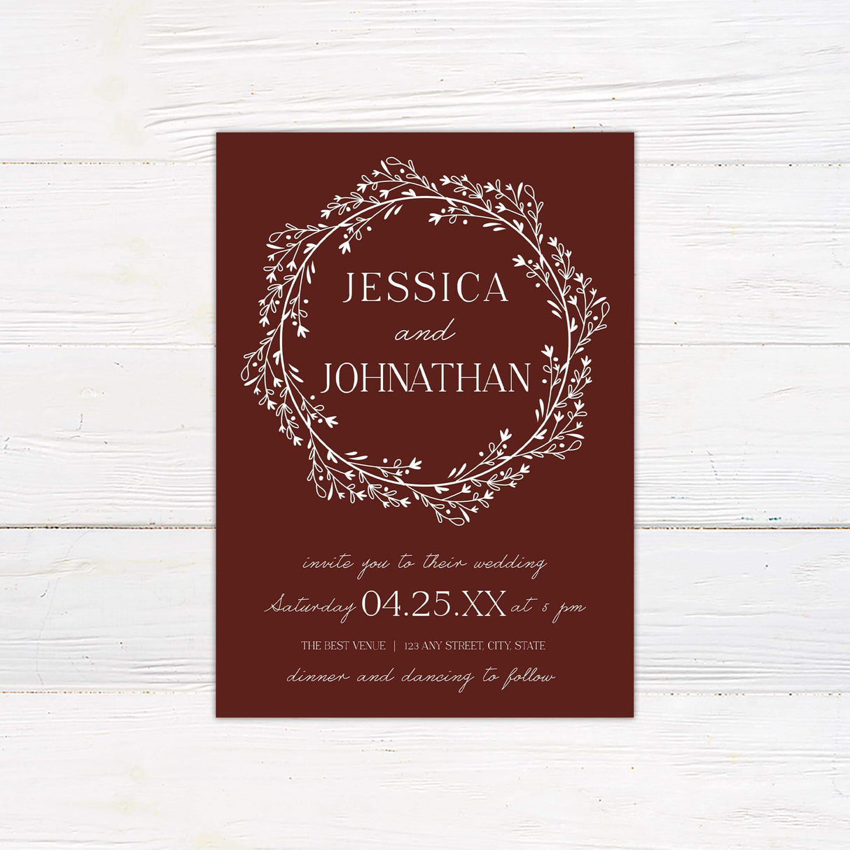 Wedding invitation with marsala red background, white floral wreath illustration, and elegant serif and script fonts for event details