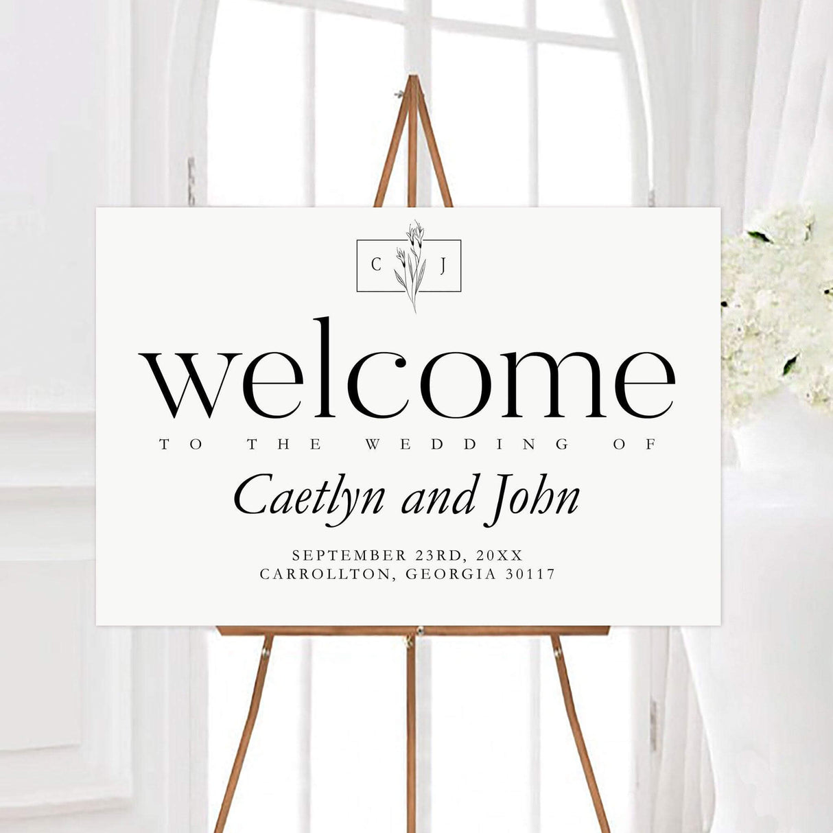 Minimal flower wedding welcome sign with a personalized floral monogram, couple names, wedding date, and location. Elegant serif typography and delicate flower line art create a timeless modern design.
