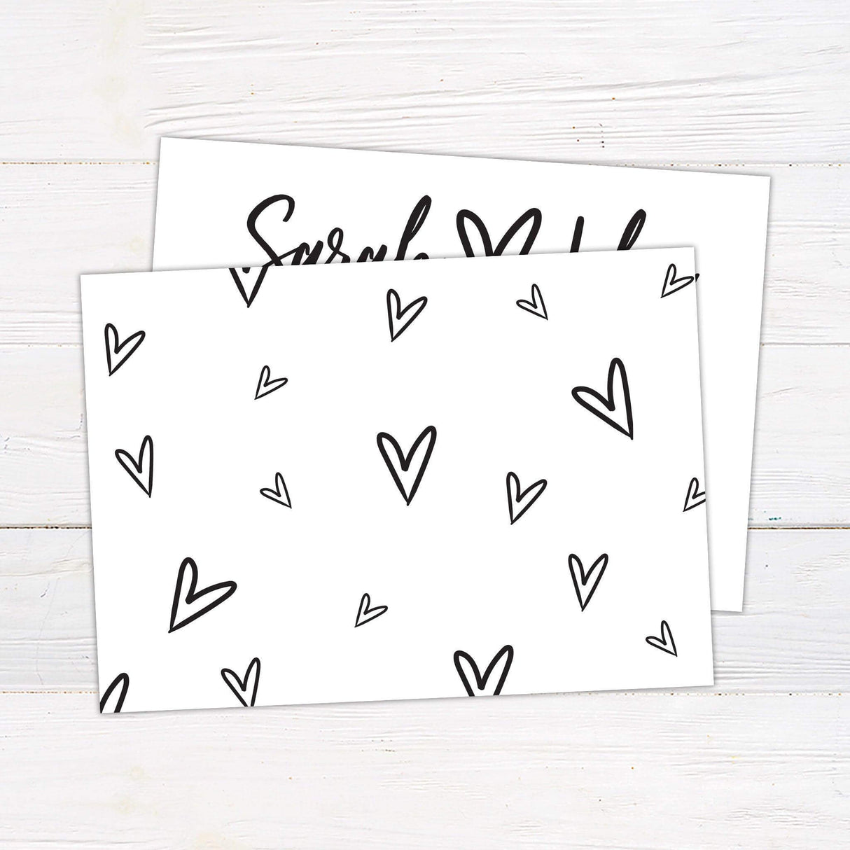 Modern black and white wedding invitation with handwritten names, heart symbol, and grid layout for date, venue, and time details - back