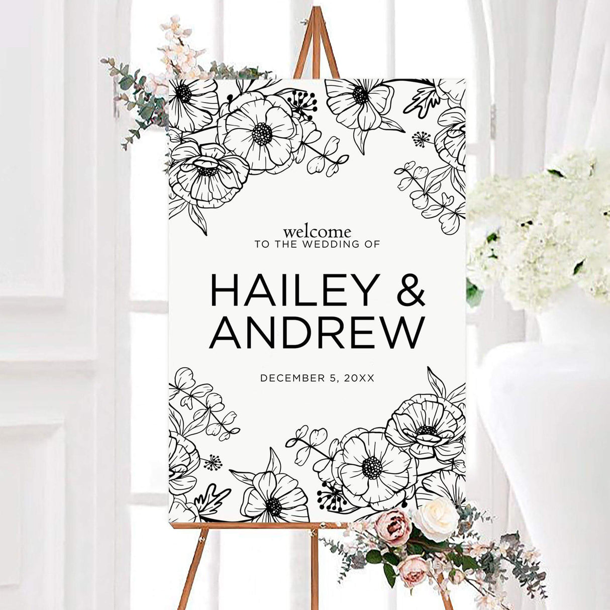 Monochrome floral wedding welcome sign with detailed botanical line drawings framing the couple’s personalized names. Modern typography displays the names and wedding date on a clean white background.