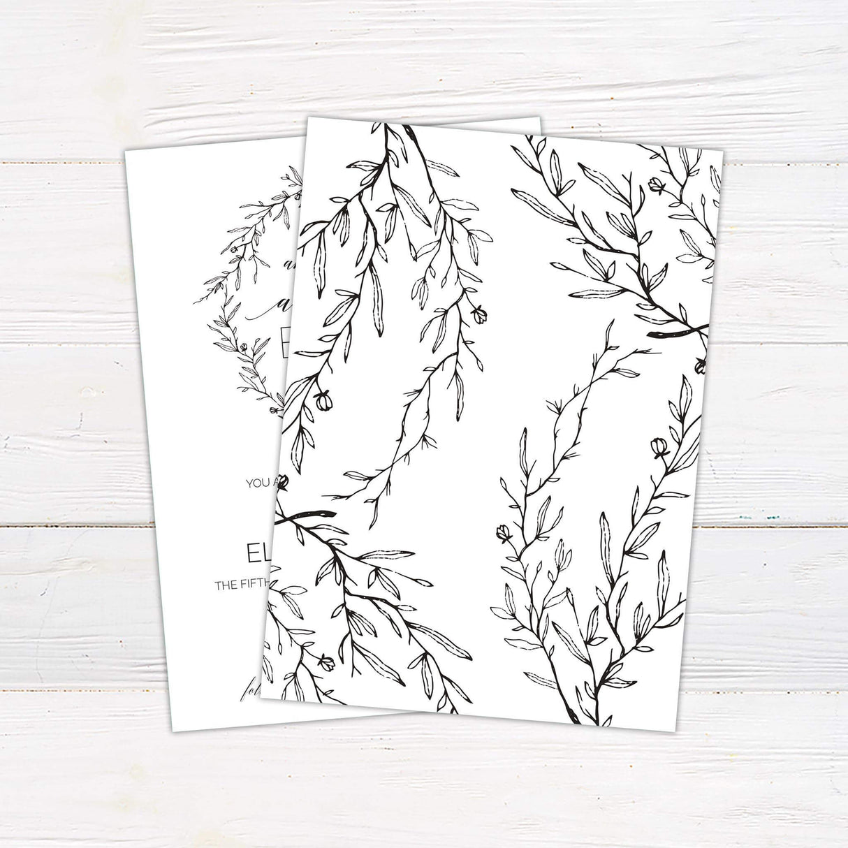 Rustic black and white wedding invitation with botanical wreath and “And so our adventure begins” quote in script and serif fonts - back side