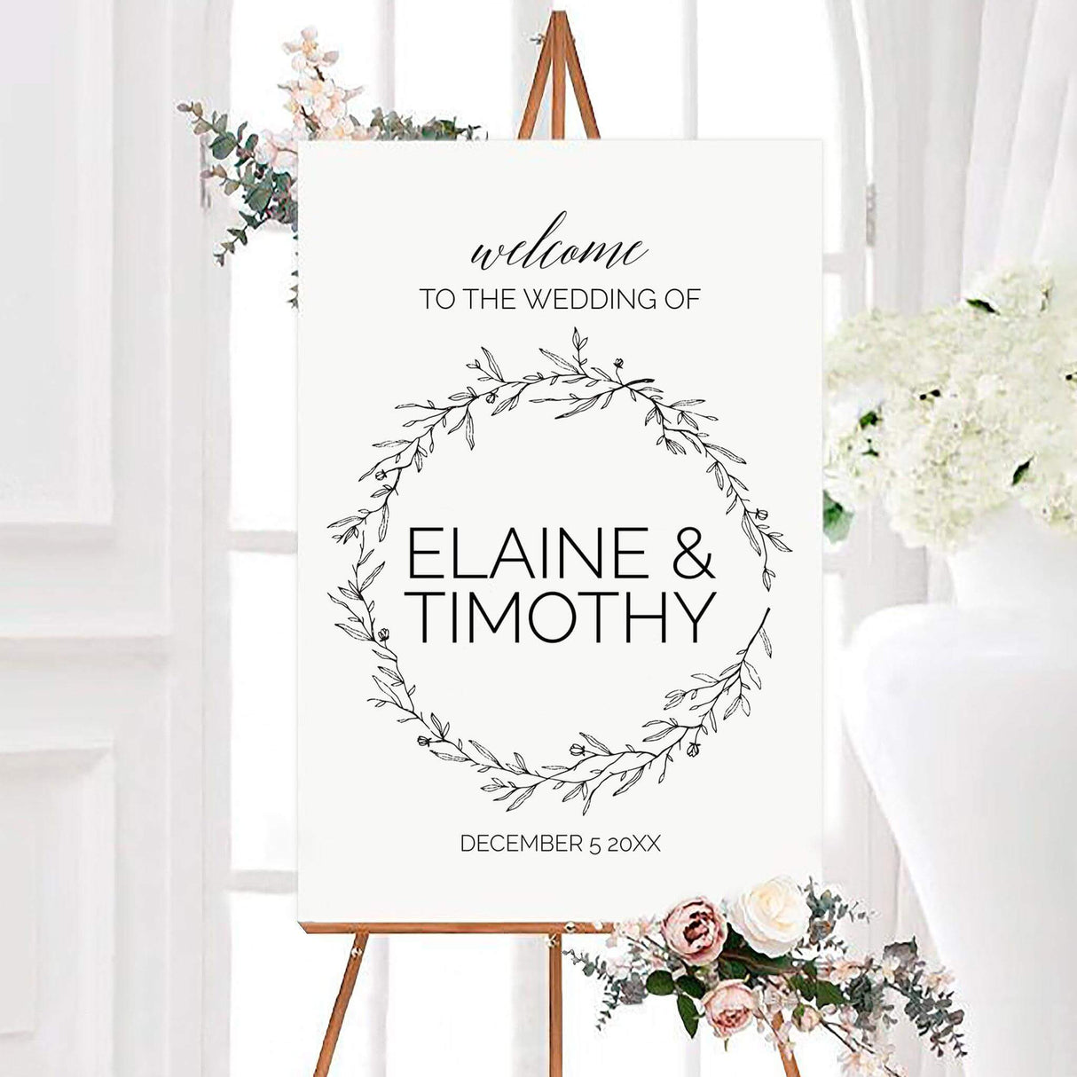 Minimalist monochrome wreath wedding welcome sign featuring a hand-drawn botanical wreath surrounding the couple’s personalized names. Black typography and a custom wedding date complete the clean, elegant design.