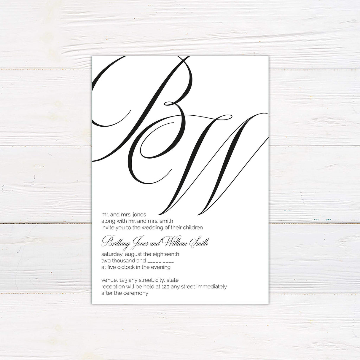 Modern wedding invitation with oversized script monogram, minimalist layout, and elegant serif and script fonts on a white background