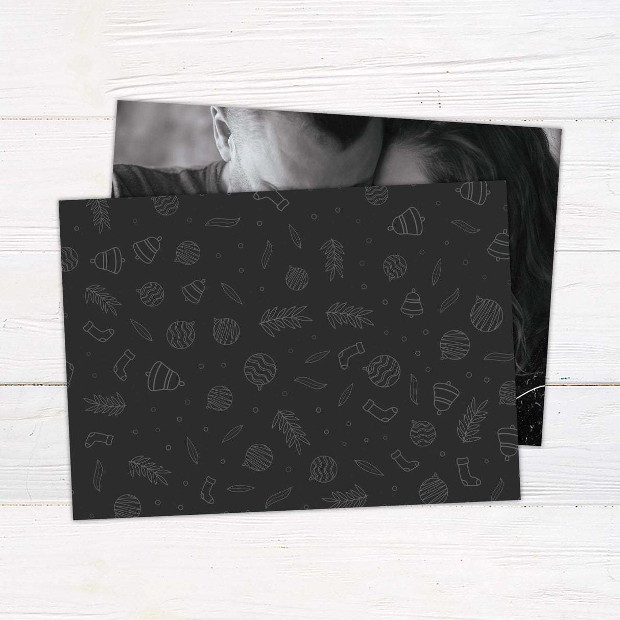 A holiday card design with a family holding their newborn baby and the words “The More the Merrier” displayed in elegant script. The card includes a customizable holiday greeting. - back.