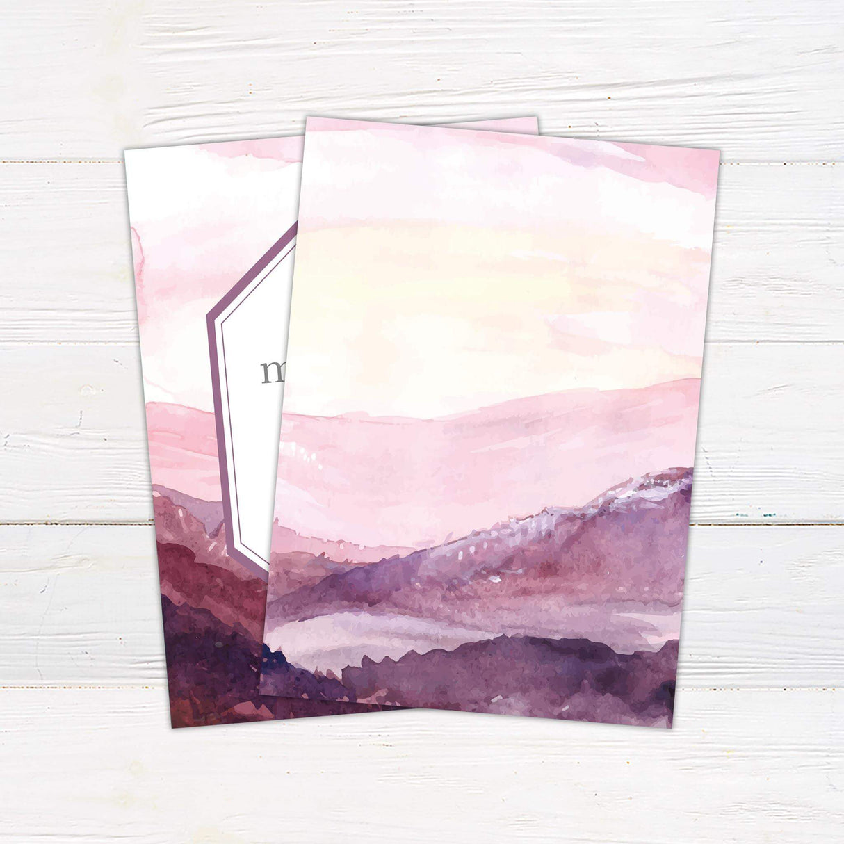 Watercolor wedding invitation with purple and pink mountain landscape at dusk, geometric frame, and elegant script and serif fonts - back side