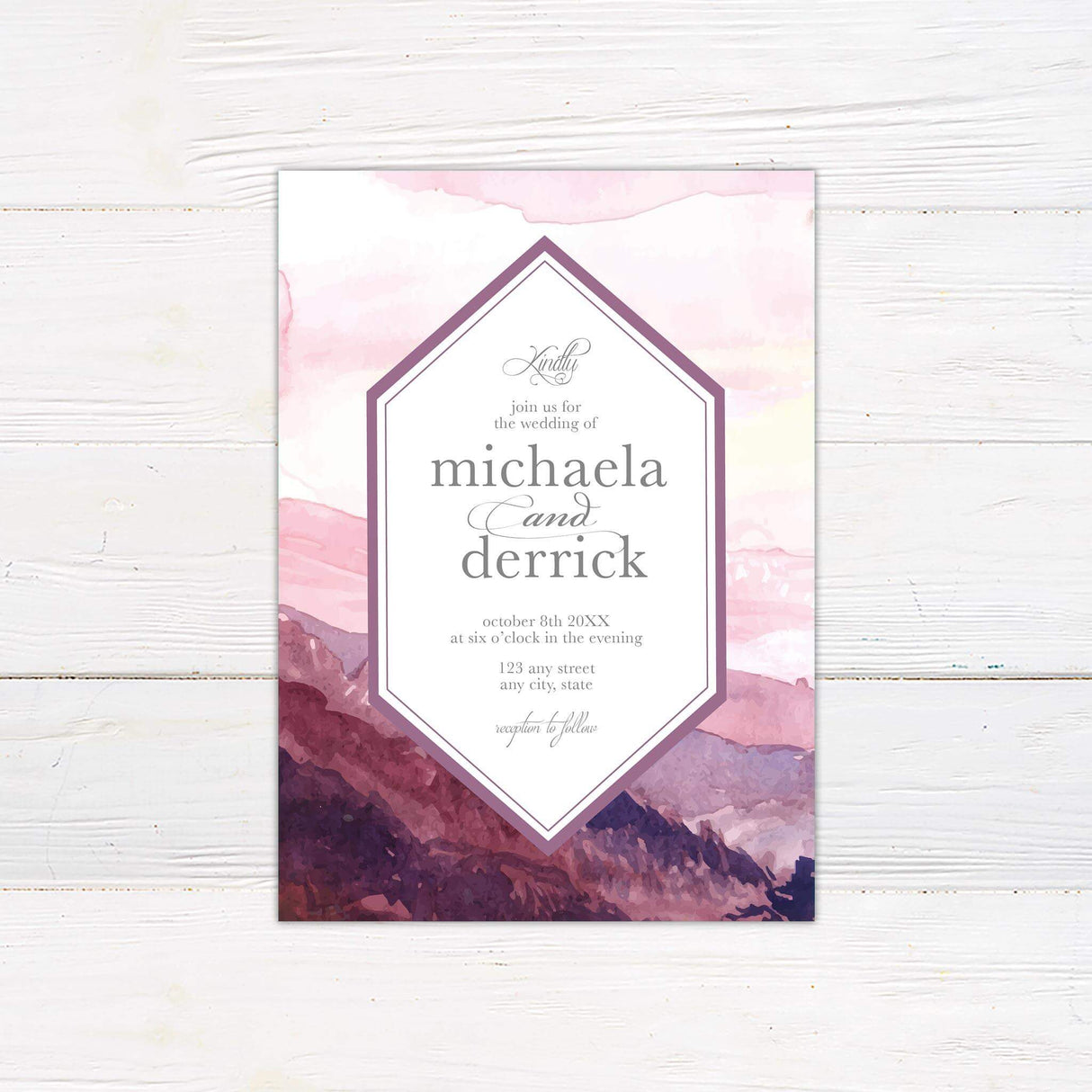 Watercolor wedding invitation with purple and pink mountain landscape at dusk, geometric frame, and elegant script and serif fonts