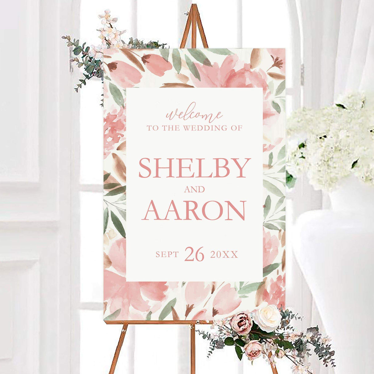 Muted floral wedding welcome sign featuring personalized couple names and wedding date on a white center panel. Muted pink flowers, sage green leaves, and soft botanical accents surround the design.
