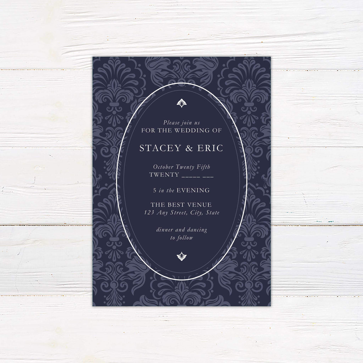 Navy wedding invitation with white oval frame, vintage damask background, and elegant serif fonts in a formal layout