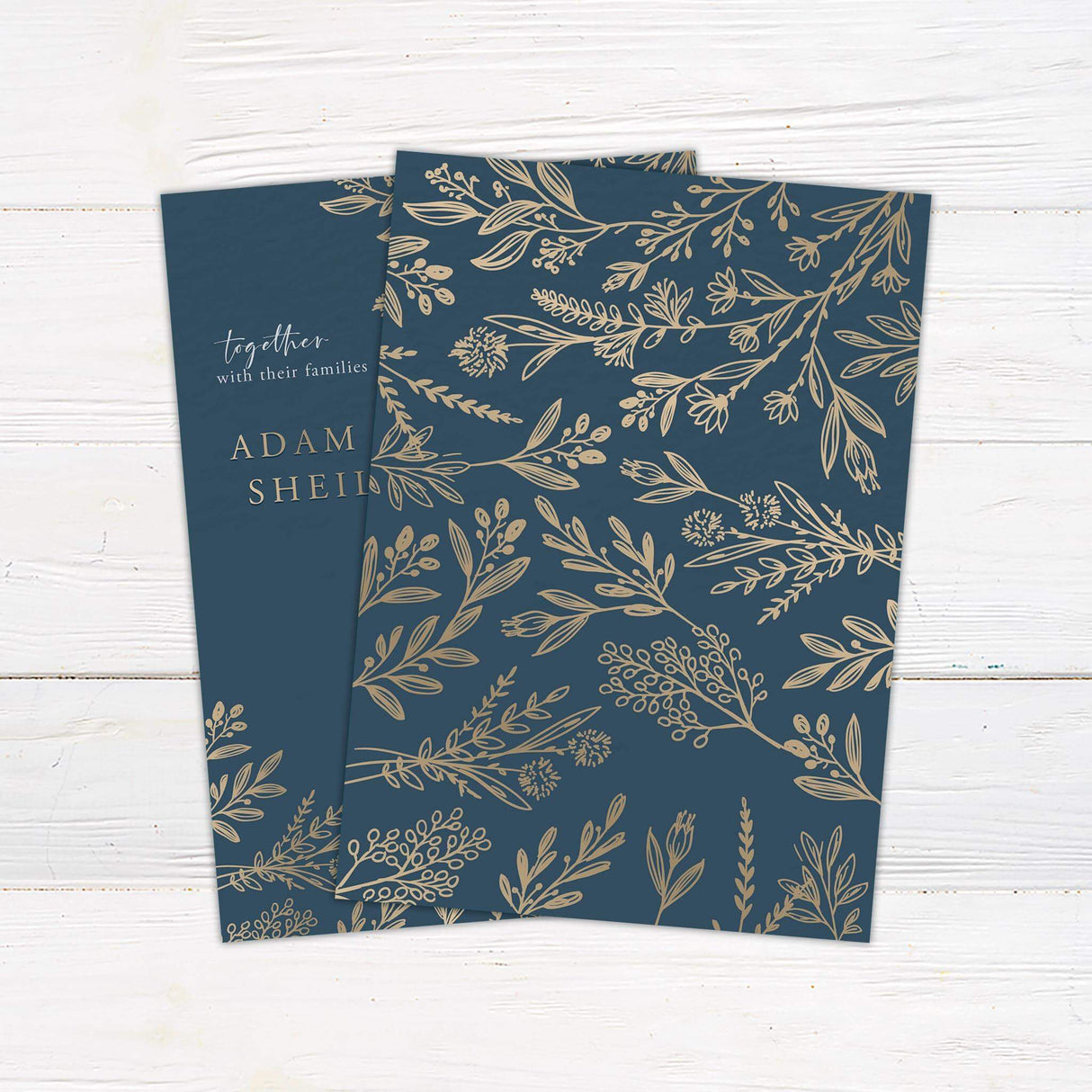 Navy and gold wedding invitation with elegant floral corner illustrations, gold serif text, and white handwritten script on a dark blue background - back side