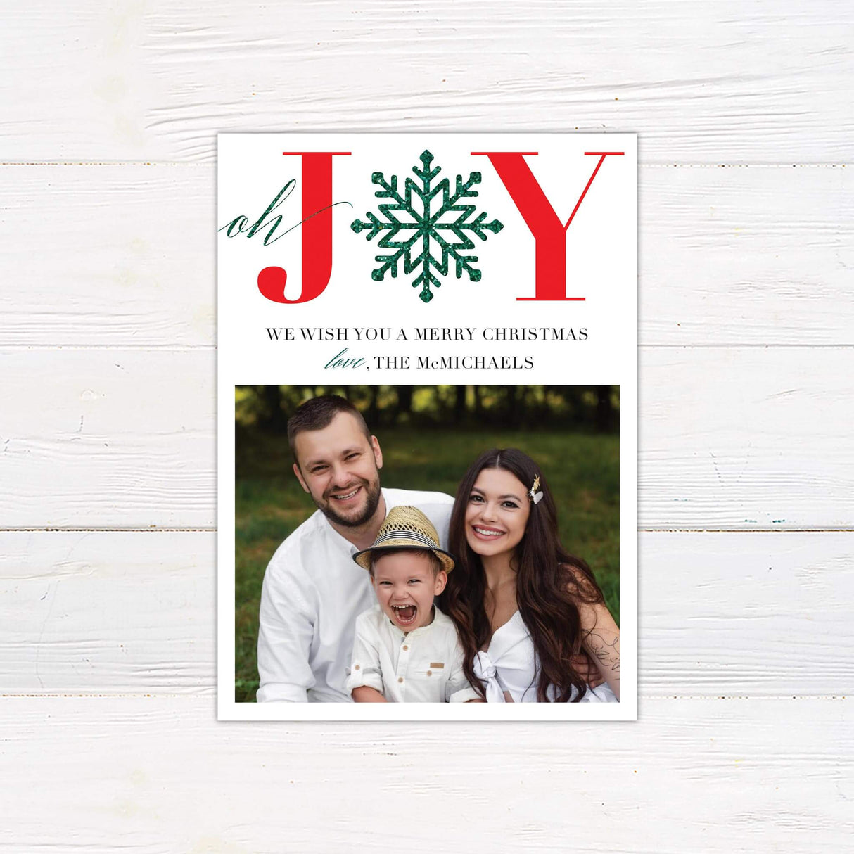 A holiday card design featuring the word “JOY” with a green snowflake, along with a family photo. A festive and customizable Christmas greeting.