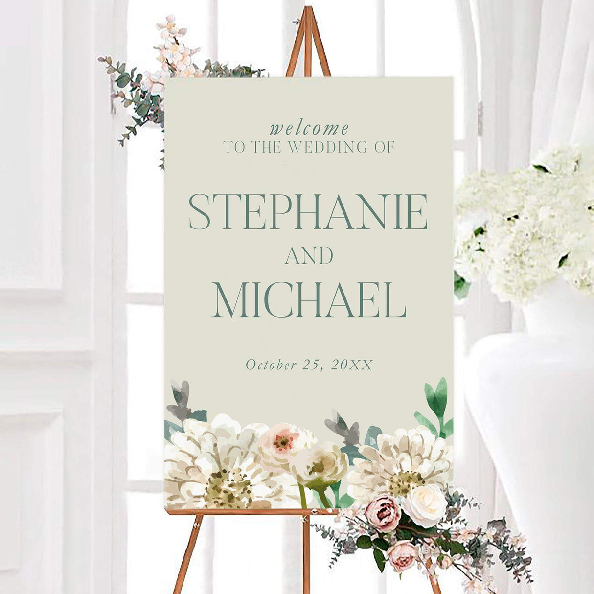 Elegant painted white floral wedding welcome sign featuring painted white and ivory flowers with soft blush accents and muted green foliage. The personalized design includes the couple’s names and wedding date in refined typography.