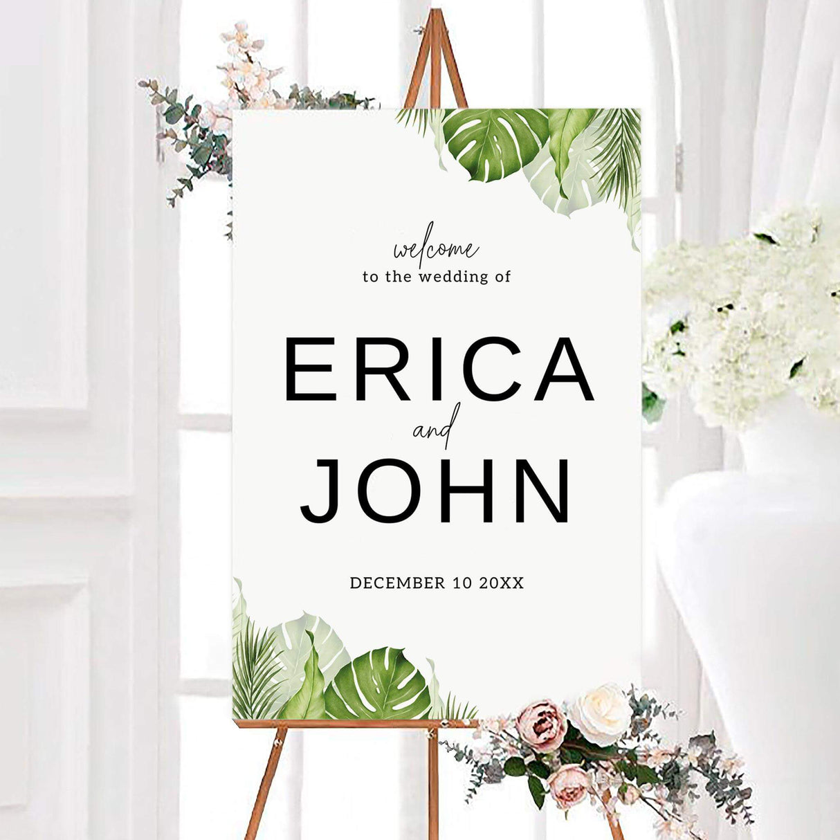 Modern tropical palm leaves wedding welcome sign with watercolor monstera leaves and palm greenery framing a clean white background. The personalized design features the couple’s names and wedding date in bold black typography.