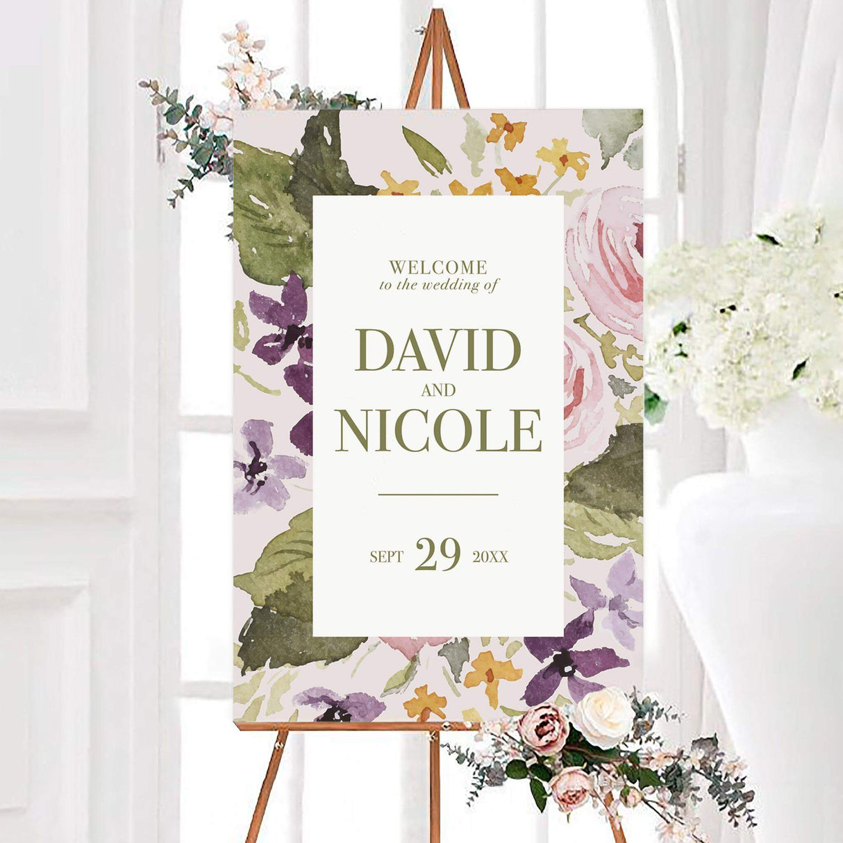 Pastel flower wedding welcome sign featuring pink and purple flowers, golden accents, and green foliage. The center features personalized couple names and a wedding date in elegant typography.