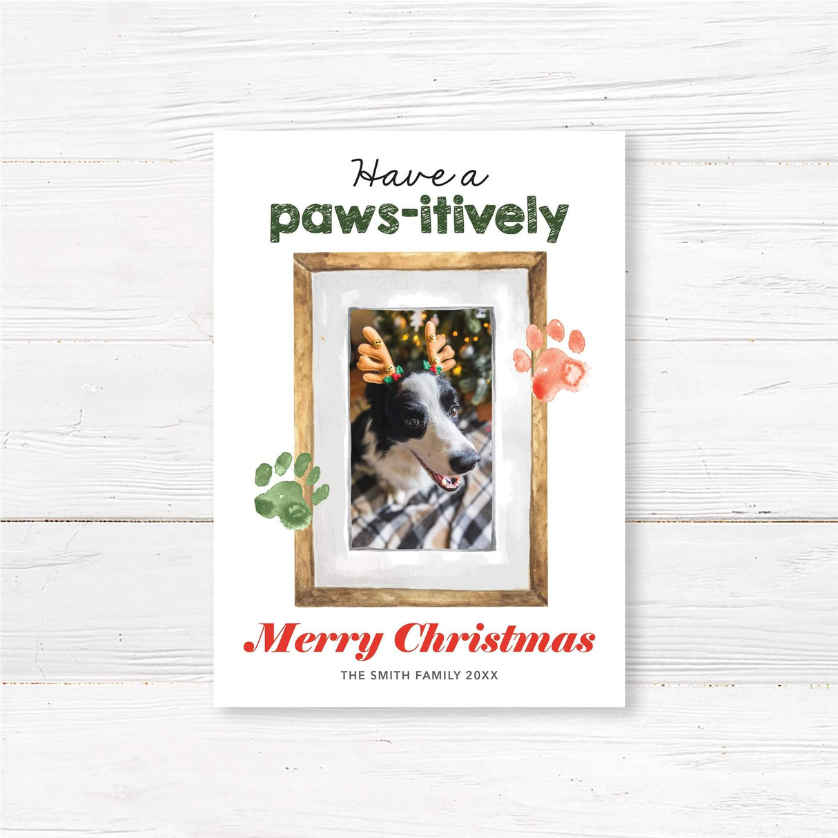 Custom pet photo Christmas card featuring a dog with reindeer antlers, watercolor paw prints, and the text "Have a Paws-itively Merry Christmas"