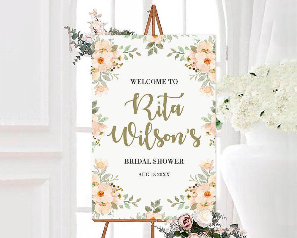 Peach floral border bridal shower invitation with elegant flowers and personalized details on easel in bright setting.