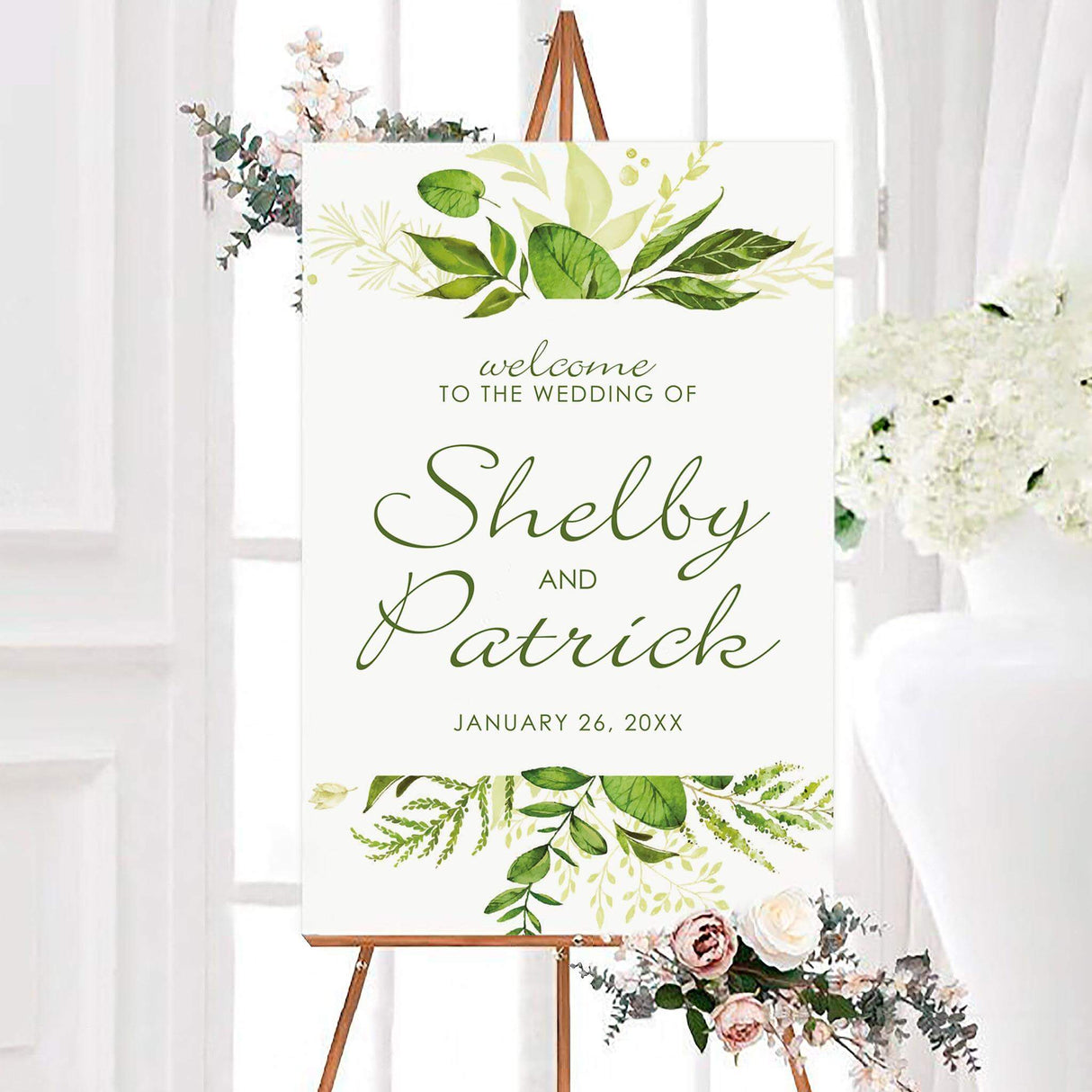 Timeless greenery wedding welcome sign featuring personalized couple names in elegant green script on a white background. Lush botanical leaves and foliage decorate the top and bottom of the design.