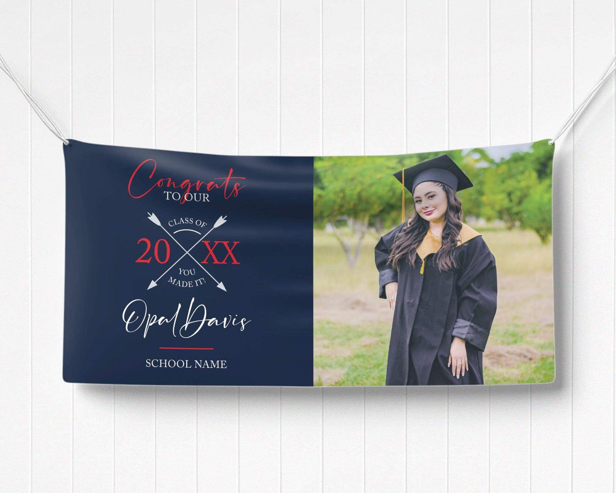 Graduation vinyl banner with split design featuring bold congratulatory text, crossed arrow class year emblem, and a custom graduate photo. Perfect for high school, college, or university graduation parties and ceremonies. Durable, weatherproof, and available in custom colors for a standout celebration. navy and red