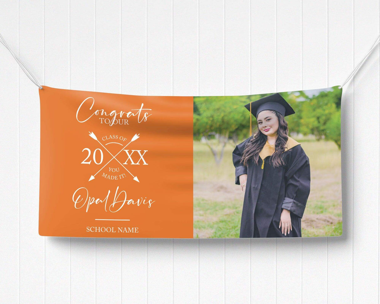 Graduation vinyl banner with split design featuring bold congratulatory text, crossed arrow class year emblem, and a custom graduate photo. Perfect for high school, college, or university graduation parties and ceremonies. Durable, weatherproof, and available in custom colors for a standout celebration. orange
