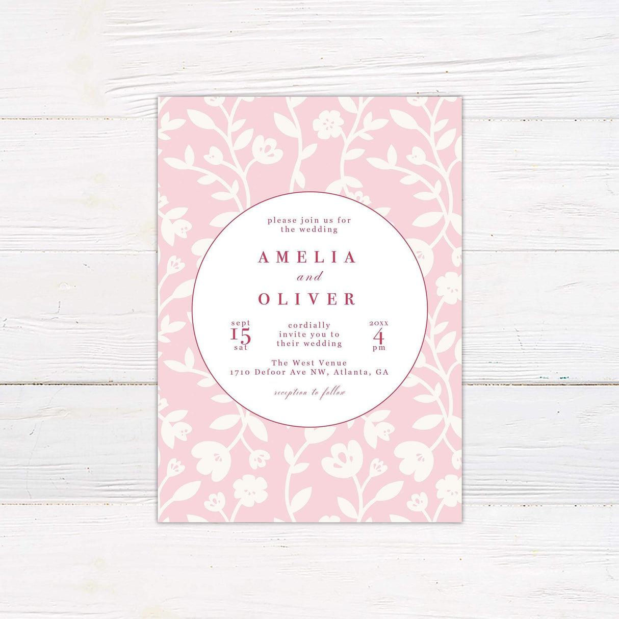 Modern pink wedding invitation with bold circle design, floral vine background, and red serif and script fonts on a blush pink backdrop.