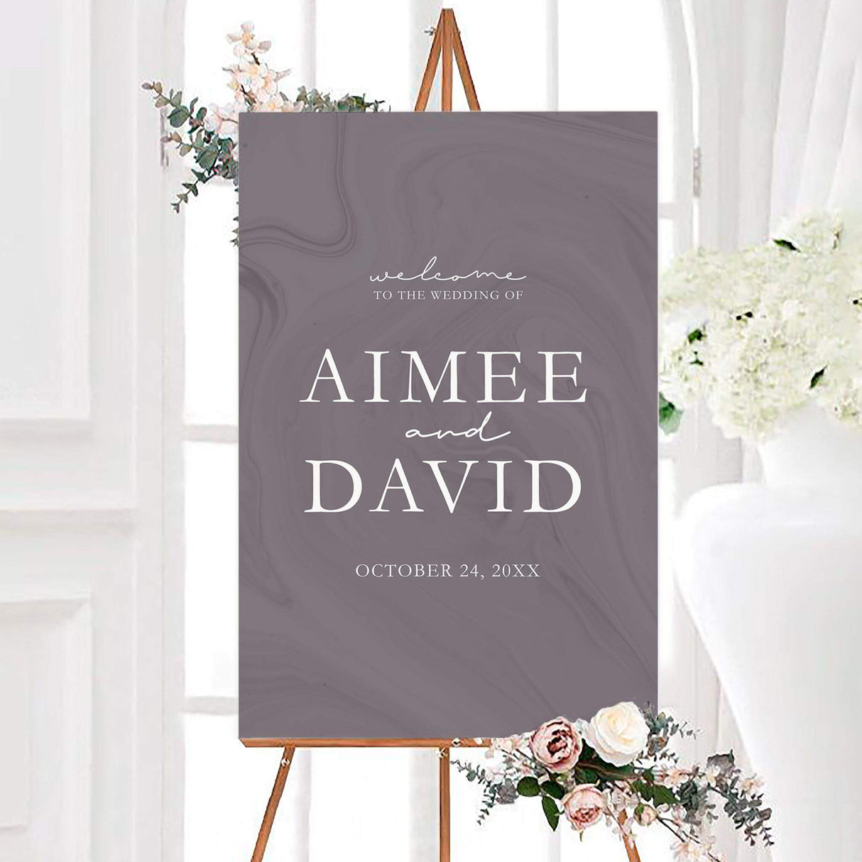 Plum marble wedding welcome sign with large white serif names and delicate handwritten accents. A personalized wedding date appears beneath the couple’s names on a muted mauve background.