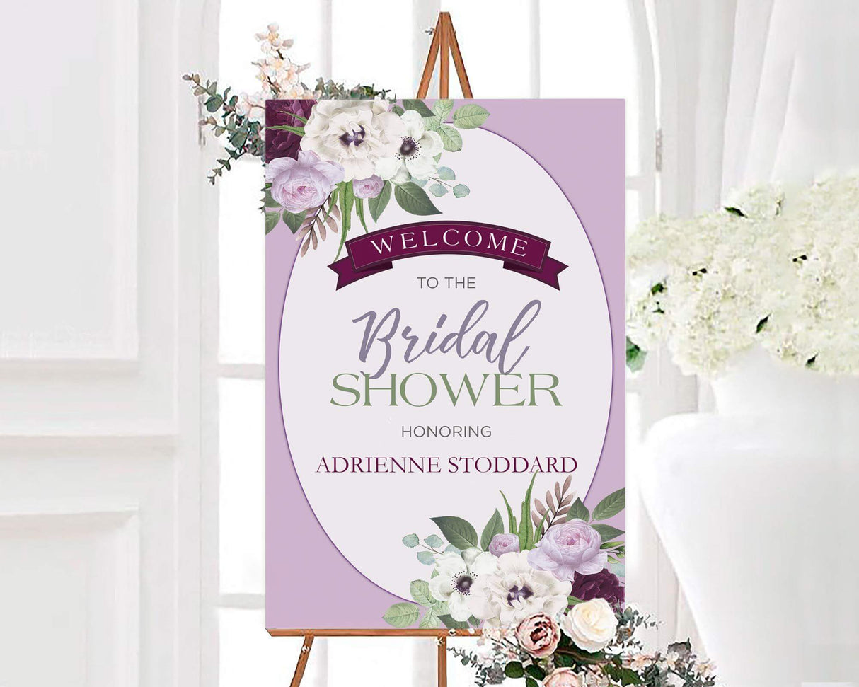 A purple bouquet bridal shower sign with purple and white watercolor flowers. The design features soft blooms and elegant text on a purple background.
