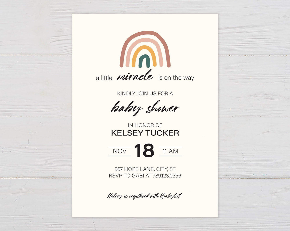 Minimalist baby shower invitation with a soft cream background. Features a hand-drawn rainbow in earthy tones of pink, mustard, and green at the top. Below, elegant typography reads "a little miracle is on the way." The main text invites guests to honor the expectant parent, with the date, time, and location provided. RSVP details are listed, along with a note about the baby registry. The design is clean and modern, with a warm and welcoming aesthetic.